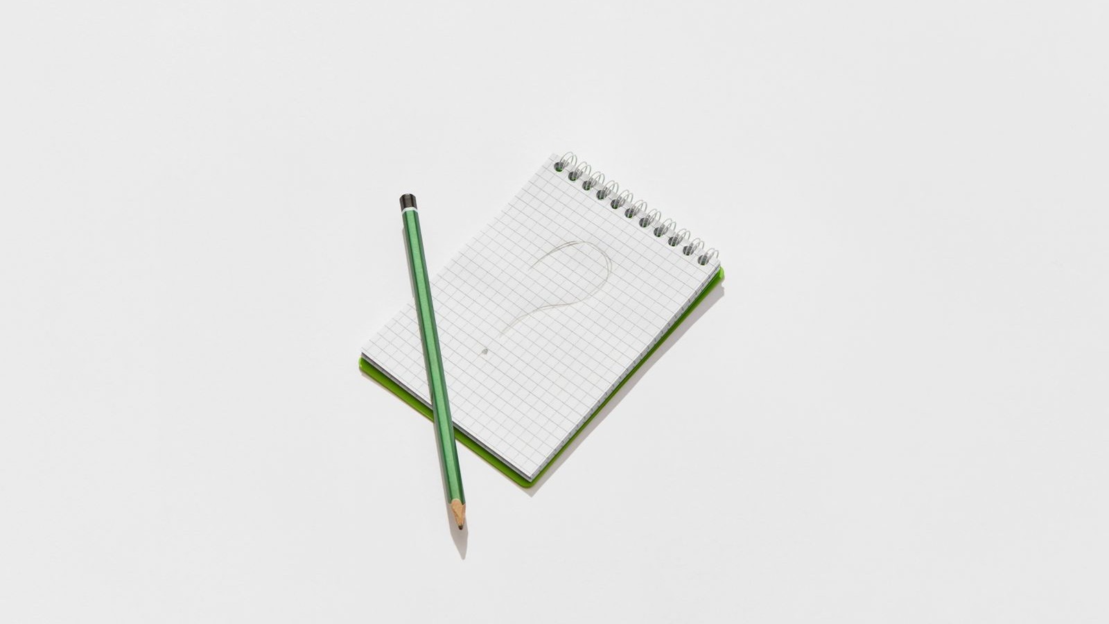 A notepad with a large question mark and a pencil on a desk.