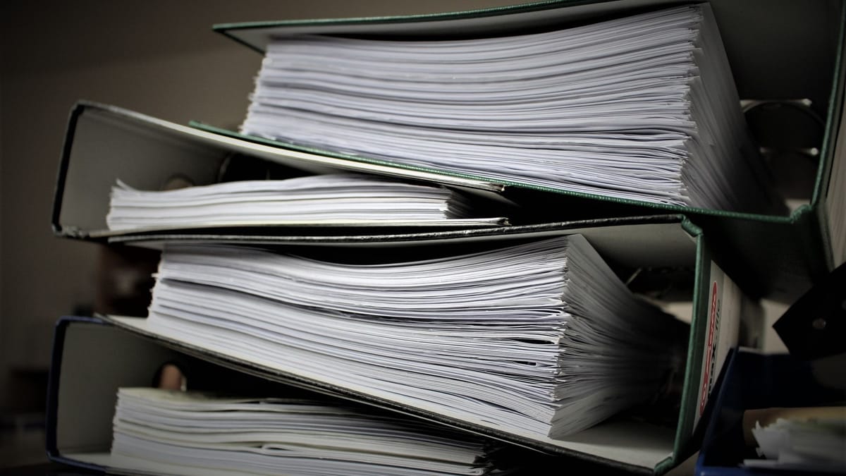 A stack of paper-filled folders on a shelf.
