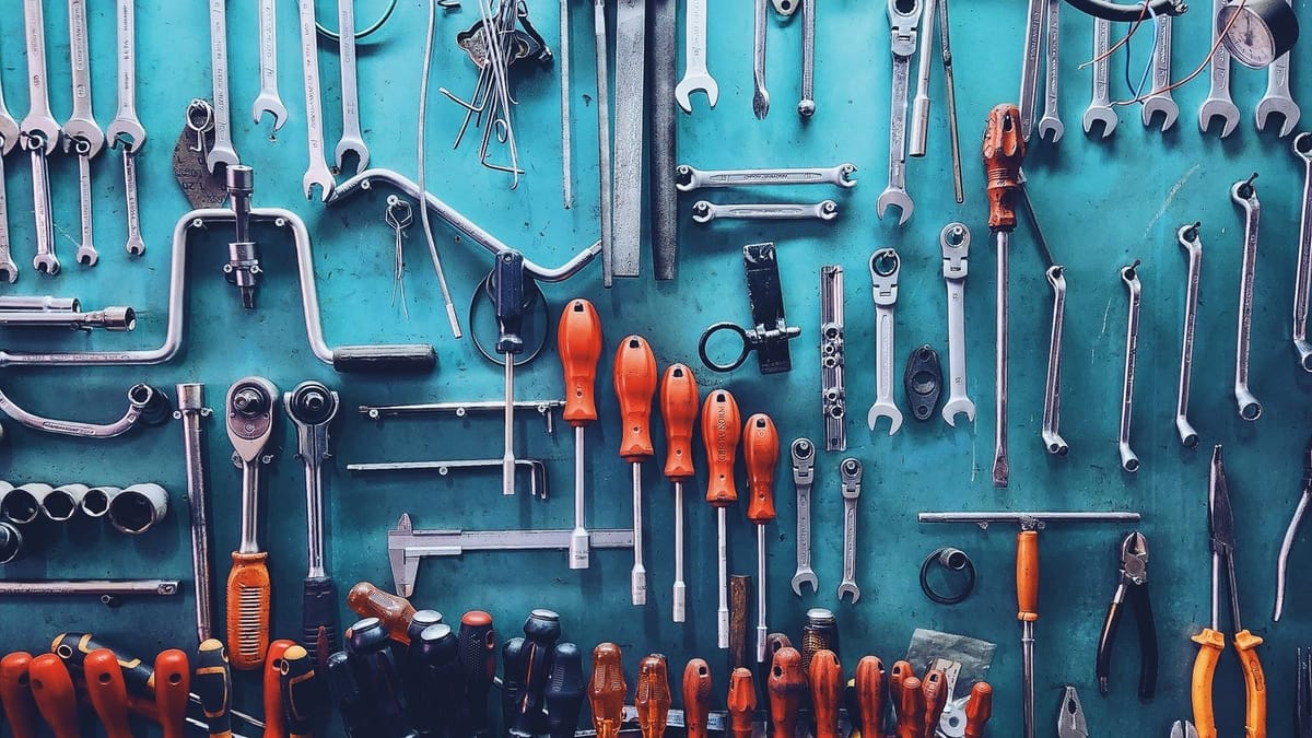 A wall of sorted hand tools hanging above a workbench.