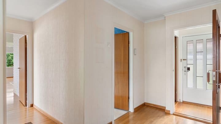 A bright apartment hallway with several open doors.